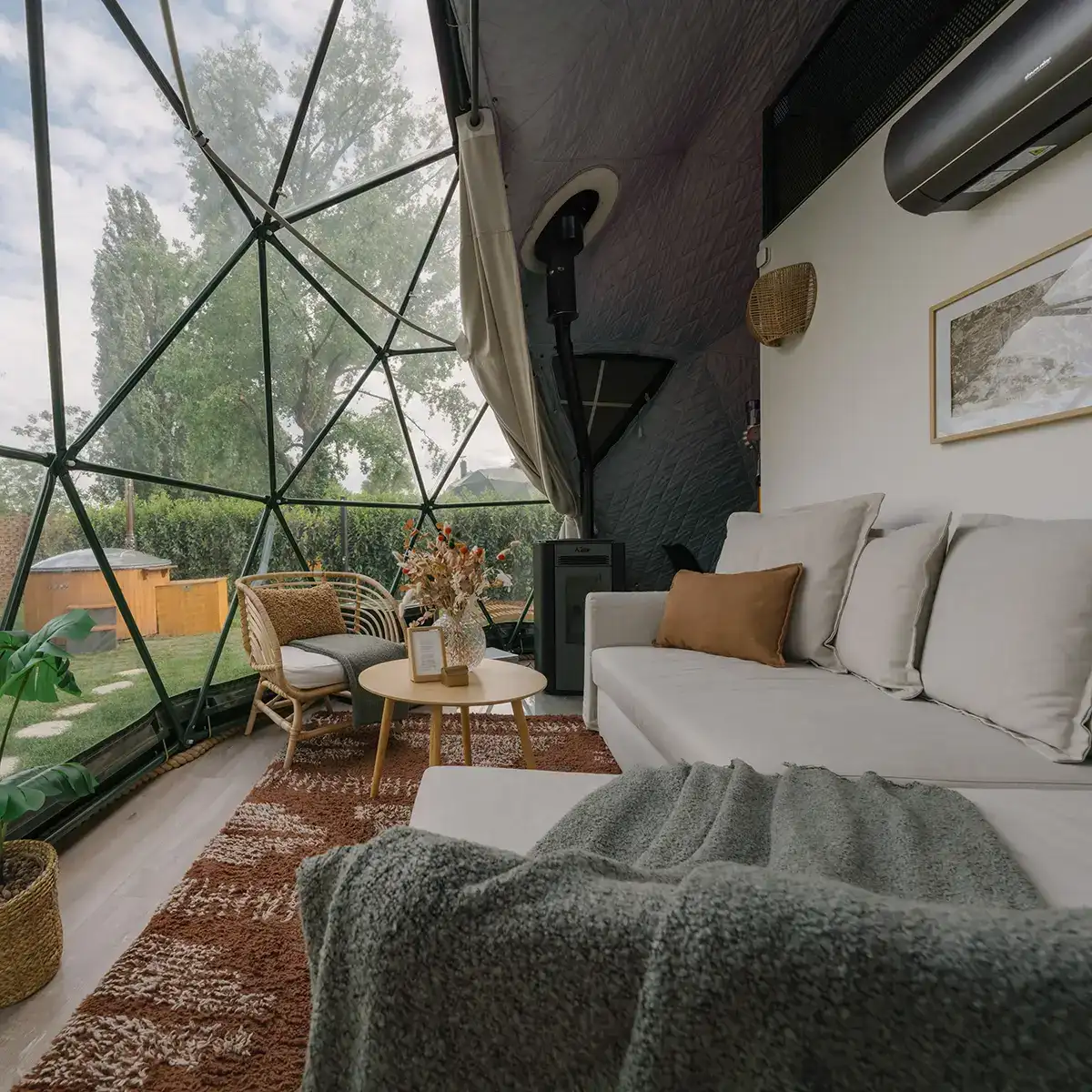 The dome's living area: a sofa and rugs by the geodesic glass facade looking out to the trees